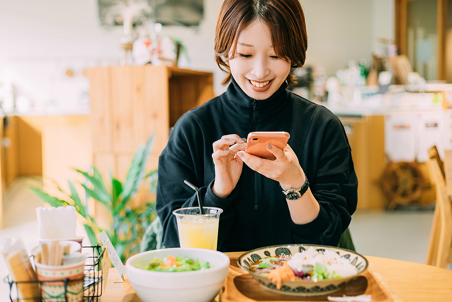 カフェで食べ物をスマホで撮影する若い女性　イメージ画像